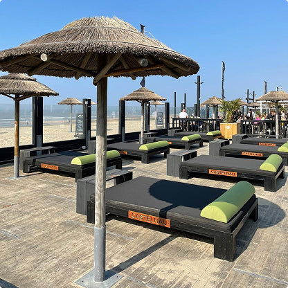 zwarte ligbed kussens met een groen hoofdkussen op ligbedden in een strandtent